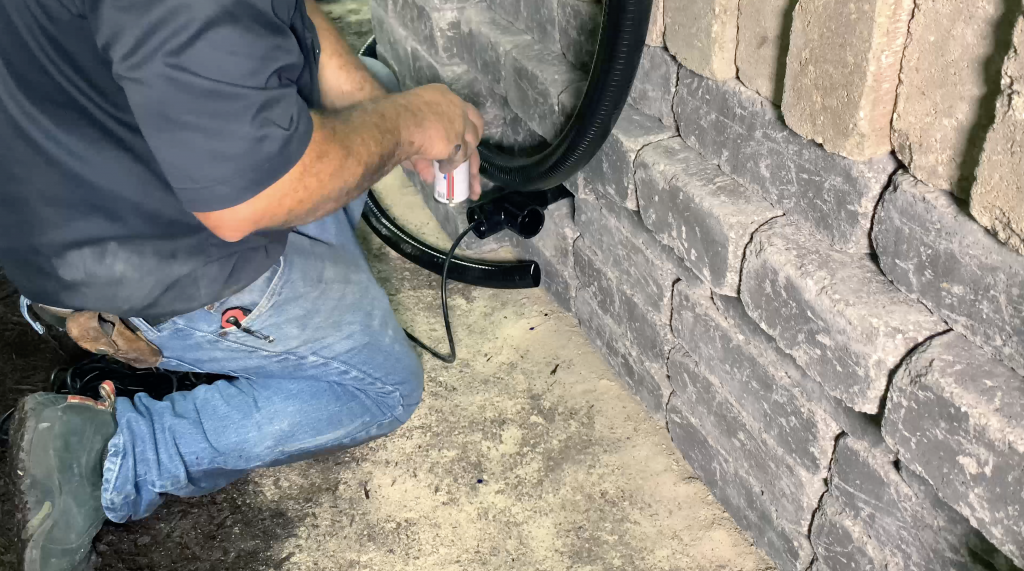 Man installing the piping on the backside of a hardscape water feature