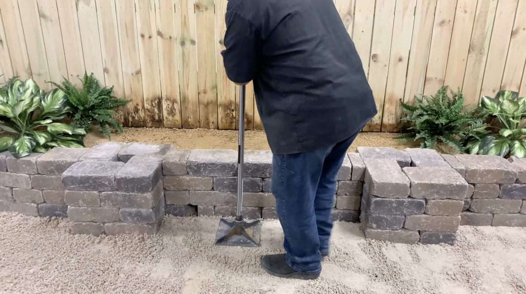 Man tamping out sand for water feature base
